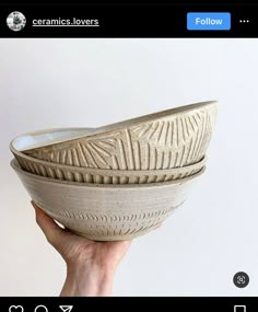 a hand holding a white bowl with designs on it