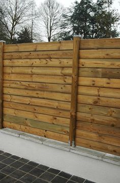 a wooden fence that is next to a sidewalk