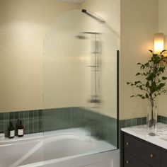 a bathroom with two sinks and a bathtub next to a vase filled with flowers