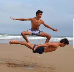 two men are doing tricks on the beach