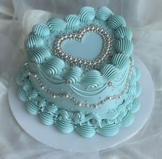 a heart shaped cake with blue icing and silver decorations on it's side