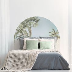 a bed with two pillows on top of it next to a round mirror and curtains