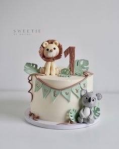 there is a cake decorated with animals on the top and one has a letter in the middle