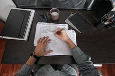 a man sitting at a table with papers and pen in his hand while writing on paper