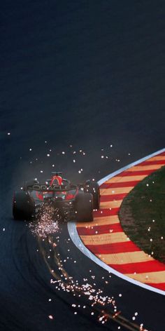 a red and white race car driving on a track with fireworks coming out of it