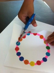 a child is making a paper circle with colored circles on it and holding a blue marker