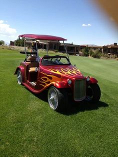 a red and yellow car with flames painted on it's hood parked in the grass