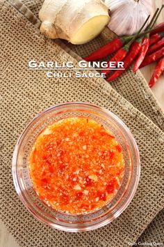 garlic ginger chili sauce in a glass bowl with red peppers and garlic on the side