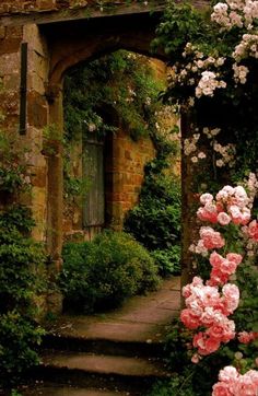 an arch in the middle of a garden with pink and white flowers on either side