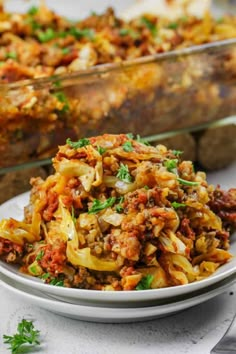 a white plate topped with pasta next to a casserole dish filled with meat