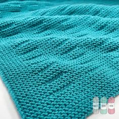 a blue knitted blanket sitting on top of a bed