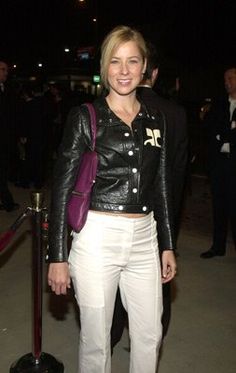 a woman wearing white pants and a black leather jacket