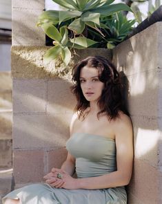 a woman in a dress sitting against a wall