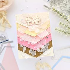 a stack of cards sitting on top of a white table next to flowers and scissors