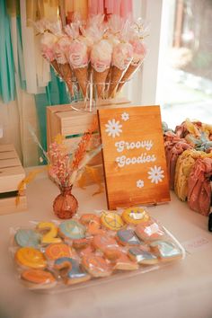 a table topped with cookies and flowers next to a sign