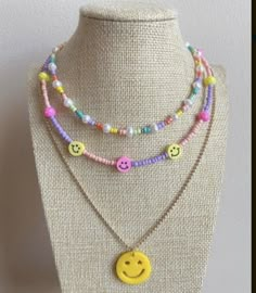 three necklaces with smiley faces on them and beads hanging from the neck, all in different colors