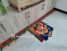 an artistic painting on the floor of a kitchen with cupboards and cabinets in the background