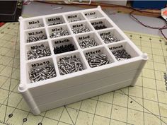 a box filled with lots of screws sitting on top of a table next to a ruler