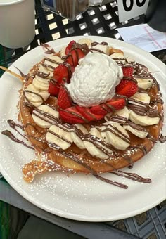 a waffle topped with bananas, strawberries and whipped cream on a white plate