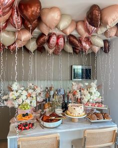 a table topped with lots of desserts and balloons hanging from the ceiling above it