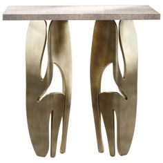 a table with two metal legs and a marble top on the bottom one is shaped like a woman's head