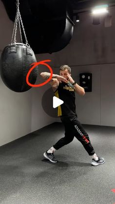 a man in black shirt and white sneakers doing a kick with a punching bag over his head