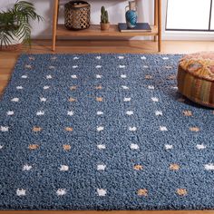 a blue rug with white stars on it in front of a wooden shelf and potted plant