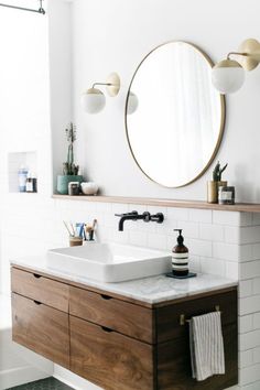 a bathroom with two sinks and a large round mirror above the sink on the wall