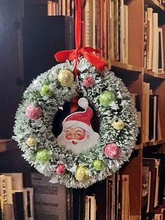 a christmas wreath hanging from the side of a bookshelf with a santa face on it