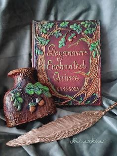 an ornate book and feather are on a bed with a satin sheet that has the words savannah's enchantid quince written in it