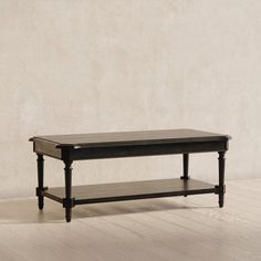 a black coffee table sitting on top of a hard wood floor next to a wall