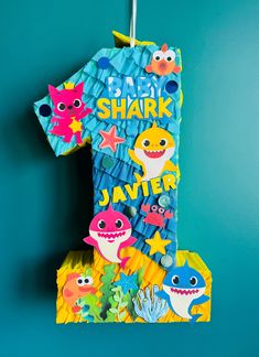 a paper shark birthday shirt hanging from a hook on a blue wall with other items