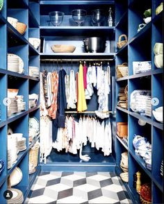 a blue closet filled with lots of different types of clothes and bowls on shelves next to each other