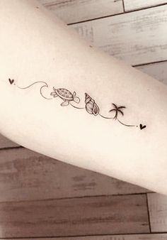 a woman's arm with a small turtle and palm trees tattoo on the left forearm