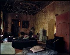 a living room filled with lots of furniture and walls covered in peeling paint on the walls