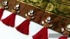 three red tassels hanging from the side of a piece of cloth with gold accents