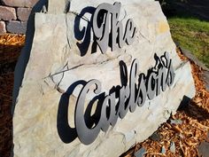 a stone sign that says the entrance to an outdoor area with wood chips and mulch