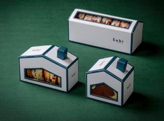 three boxes that have food inside of them on a green surface with the lids open