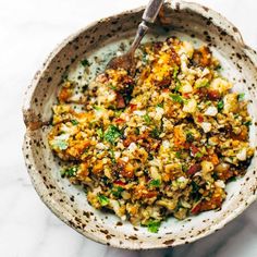 a bowl filled with food sitting on top of a white marble counter next to a spoon