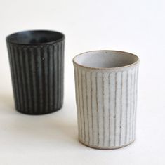 two black and white cups sitting next to each other on top of a white table