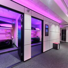 an empty room with purple lighting in the ceiling and doors open to let people know where they are going