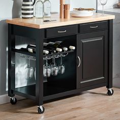 a kitchen island with wine glasses and bottles on the top, in front of a wall