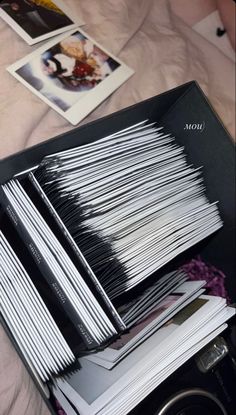 a stack of books sitting on top of a bed next to an open book case