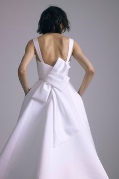 the back of a woman's white wedding dress with a large bow at the waist