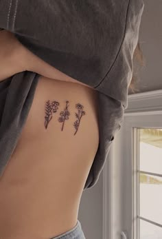 the back of a woman's stomach with three small flowers on it