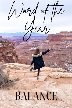 a woman standing on top of a cliff with her arms in the air and text reading word of the year balance