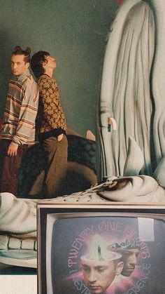 two people standing next to each other in front of a tv with an advertisement on it