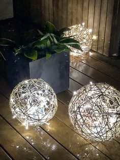 three balls with lights are sitting on a wooden floor next to a potted plant