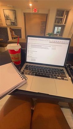 an open laptop computer sitting on top of a desk next to a cup of coffee