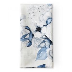 a blue and white flowered napkin on top of a white tablecloth with black dots